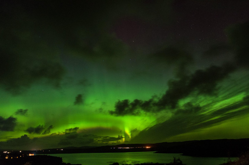 The Northern Lights (Aurora Borealis) dance in green hues over Loch Harport, Portnalong, Isle of Skye, Scotland