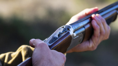 Hands of a hunter loading a hunting shotgun.