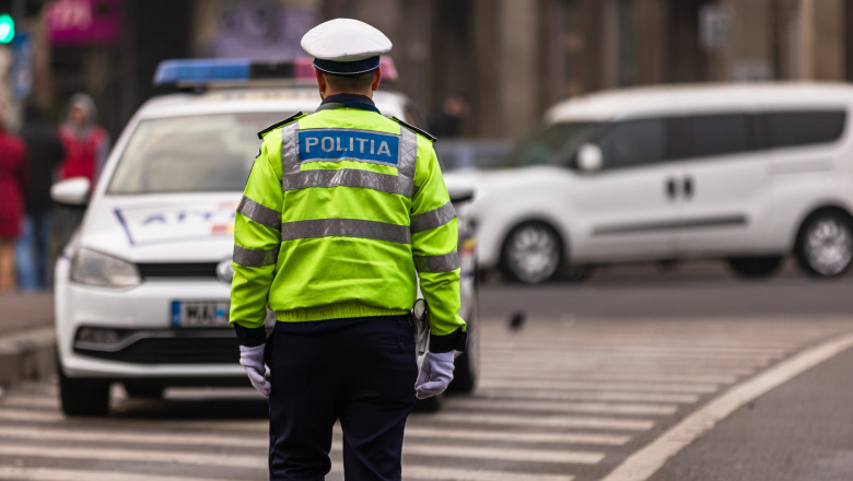 polițist în intersecție și mașin de poliție