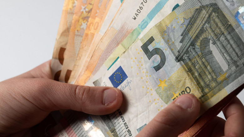 Hand holding a pile of euro cash banknotes