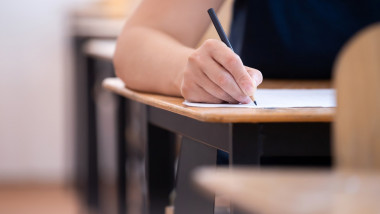 Student writing final exam in classroom.