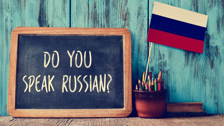 a chalkboard with the question do you speak russian? written in it, a pot with pencils, some books and the flag of Russia, on a