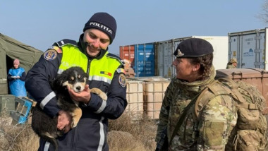 politist cu un catel in brate, alaturi de un militar britanic