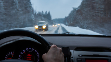 barbat conduce masina pe o strada cu zapada iarna