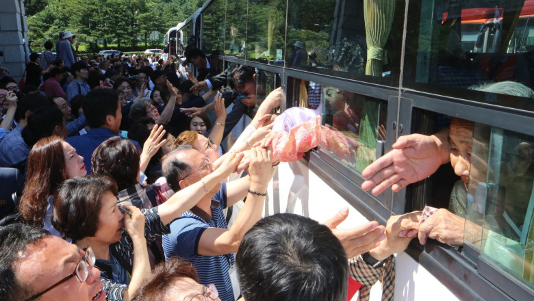 North Koreans (on bus) hold the hands of their South Korean relatives as they bid farewell at the end of a three-day family reunion event at North Korea's Mount Kumgang resort on August 26, 2018