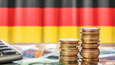 Euro banknotes and coins in front of the national flag of Germany