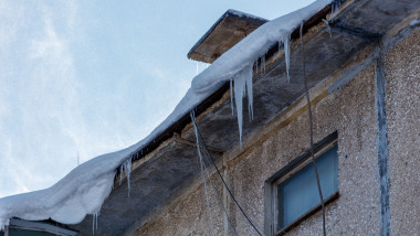 A,Building,With,Icicles,Hanging,From,The,Roof.,The,Building