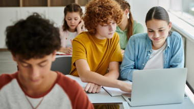 Redhead,Schoolboy,Using,Laptop,With,Smiling,Classmate,Together,During,Lesson