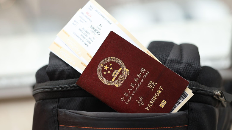 Red passport of People Republic of China with airline tickets on backpack close up. PRC passport. Red passport of People Republic of China with