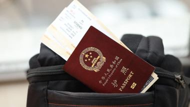 Red passport of People Republic of China with airline tickets on backpack close up. PRC passport. Red passport of People Republic of China with