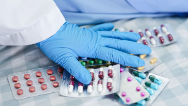 Asian doctor holding antibiotics capsule pills in blister packaging for treatment infection patient in hospital, Pharmacy drugstore concept.