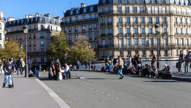 Paris with beautiful buildings, cars and people passing by on the street. Paris, France - February 10, 2025