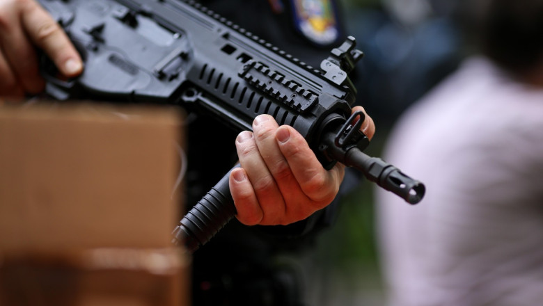 Details with the hands of a man holding an automatic rifle