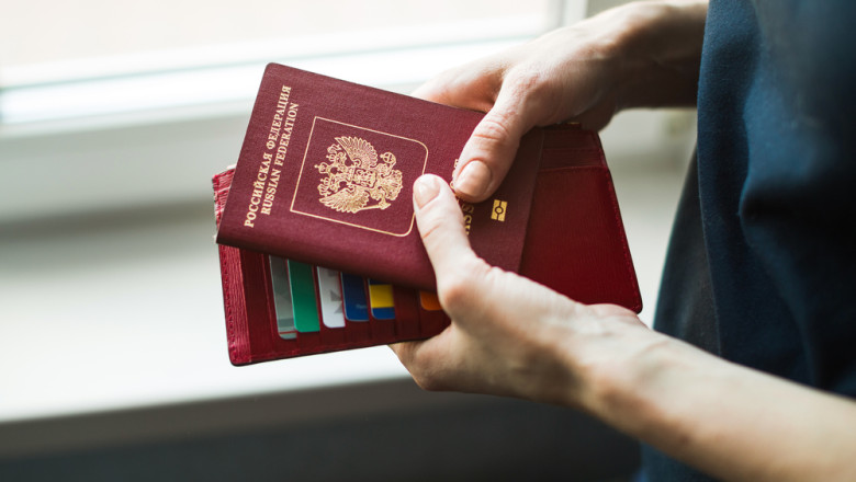 Woman,Holds,Foreign,Passport,At,Home,By,The,Window