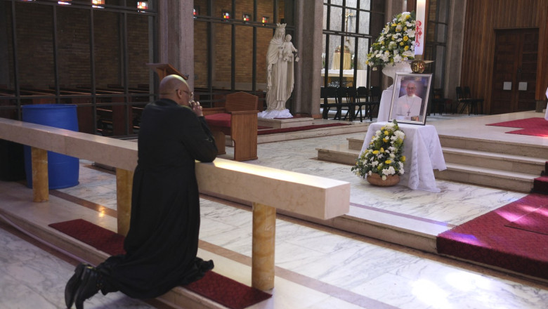 Father Lawrence Mduduzi Ndlovu prays in front of a shrine dedicated to the late Pope Francis at the Cathedral of Christ the King Catholic Church in Johannesburg on April 21, 2025.