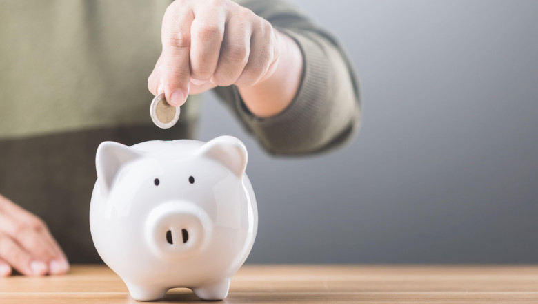 A man drops a coin into a white piggy bank