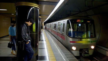 Passengers waiting for subway train arriving at underground platform in the Tokyo Metro railway transportation system in Japan