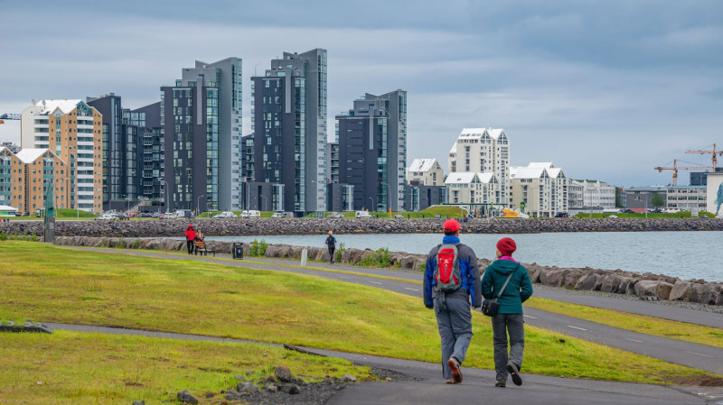 Reykjavik, Iceland - July 4, 2018: Couple of tourists walking at historical modern downtown in Reykjavik at Summer in Iceland, dramatic panoramic scen