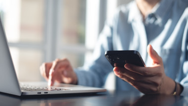 barbat cu telefon la laptop