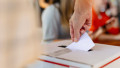 Close-up,Of,Hand,Placing,Ballot,Into,Voting,Box,At,Election.