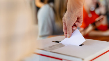 Close-up,Of,Hand,Placing,Ballot,Into,Voting,Box,At,Election.