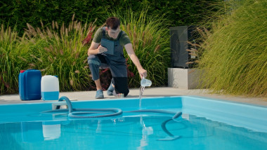 Pool,Technician,Pouring,Liquid,Into,The,Pool,While,Using,A