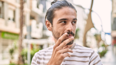 un barbat fumeaza pe strada