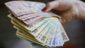 o femeie cu bancnote de lei in mana