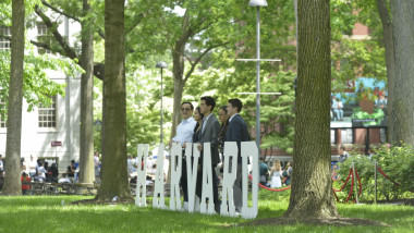 studenti si un semn de la universitatea harvard