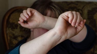 Woman covering her face in fear of domestic violence. An adult woman in a chair with two hands closes from beating. Domestic domestic violence. Select