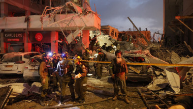 Responders work beside a damaged building following a strike by an Iranian missile in the Israeli city of Bat Yam