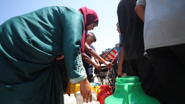 Displaced Palestinians in Gaza transport water delivered by tankers to their tents