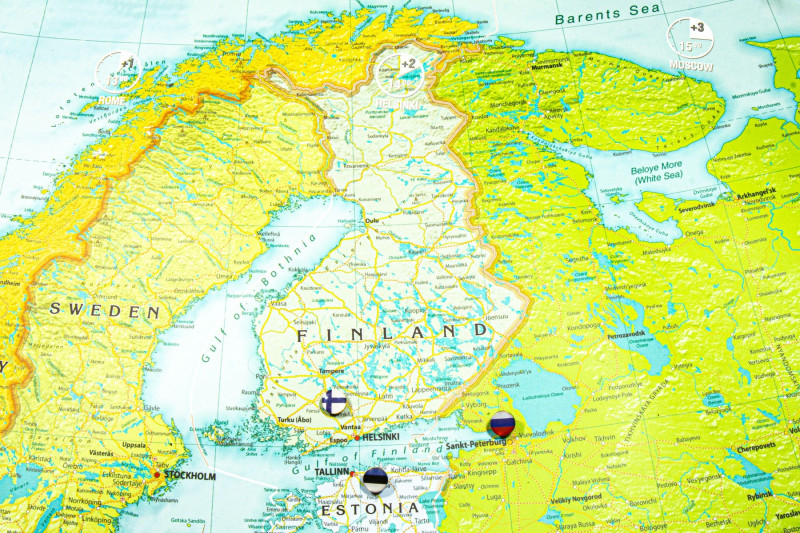Finland national flag pinned on Europe map. Macro Close up picture of country on a colorful and Blurry World Map Globe with focus to capital Helsinki.