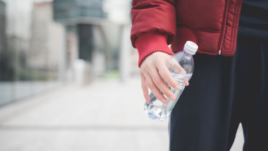 Cropped shot of young man with water bottle outside city office