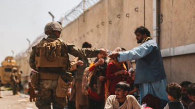 A Marine with the 24th Marine Expeditionary unit (MEU) passes out water to evacuees during an evacuation at Hamid Karzai International Airport, Kabul, Afghanistan, August 22, 2021. US service members are assisting the Department of State with a Non-combat