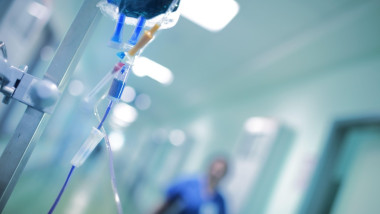Intravenous drip with blue liquid ready to use on the background of walking around medical doctor, concept of mersy killing.
