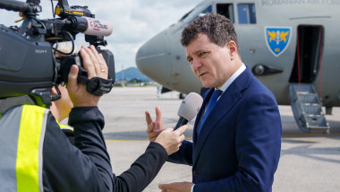 Nicusor dan da declaratii unui cameraman pe pista, avion militar in spate