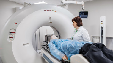 Specialists are preparing the young woman for radiation therapy by putting a special mask on him and performing a CT scan