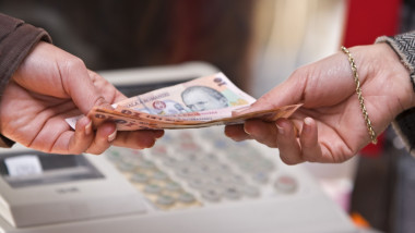 Detail of a woman's hand while she is paying in shop (Romanian money).