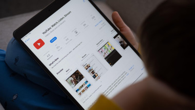 YouTube app seen on the screen of ipad which is in the hands of bored unrecognisable child. Concept. Stafford, United Kingdom, May 18, 2021.