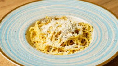 A traditional Italian spaghetti cacio e pepe dish, featuring al dente pasta coated in a creamy blend of Pecorino Romano cheese and freshly ground blac