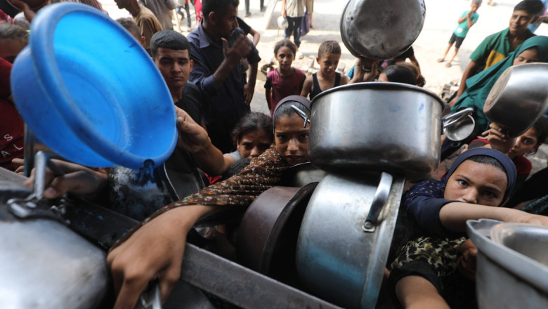 Palestinians wait to receive food from a charity kitchen, amid a hunger crisis, in Bureij
