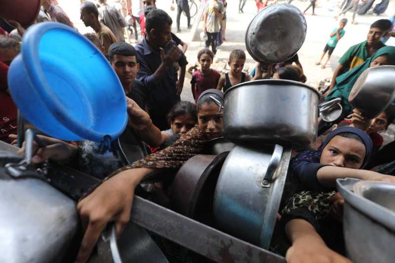 Palestinians wait to receive food from a charity kitchen, amid a hunger crisis, in Bureij