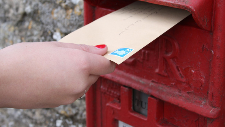 Posting a letter in an Royal mail post box.