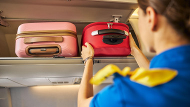 Stewardess putting a suitcase into an overhead compartment