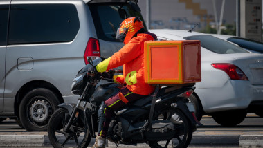 A food delivery courier is driving an order to a customer's home on a moped. takeaway food during quarantine. transport delivery of parcels at home. m