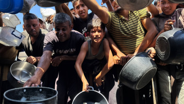 Palestinians wait to receive food from a charity kitchen, amid a hunger crisis