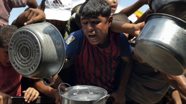 Palestinians wait to receive food from a charity kitchen, amid a hunger crisis