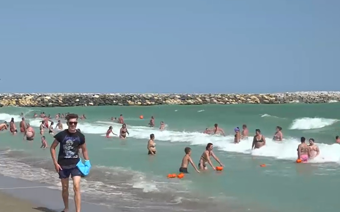 Turist scos cu forța din apă și încătușat de jandarmi, în stațiunea Venus. Pe litoral sunt valuri mari și e arborat steagul roșu