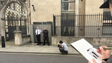 An artist draws the scene, where two security guards are standing next to the wall where a new artwork by artist Banksy has already been covered up at the Royal Courts of Justice in London. The artwork shows a judge attacking a protester with a gavel is o